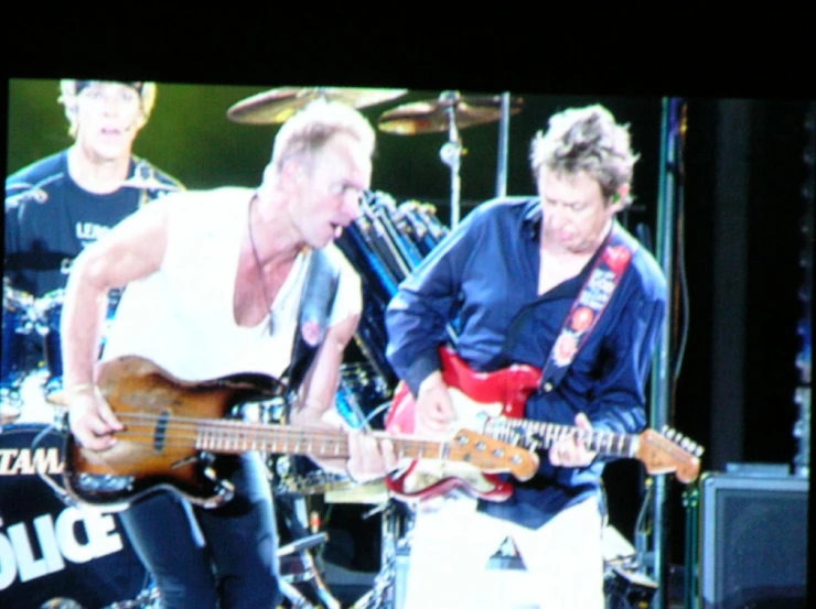 two men that are playing guitars in front of microphones