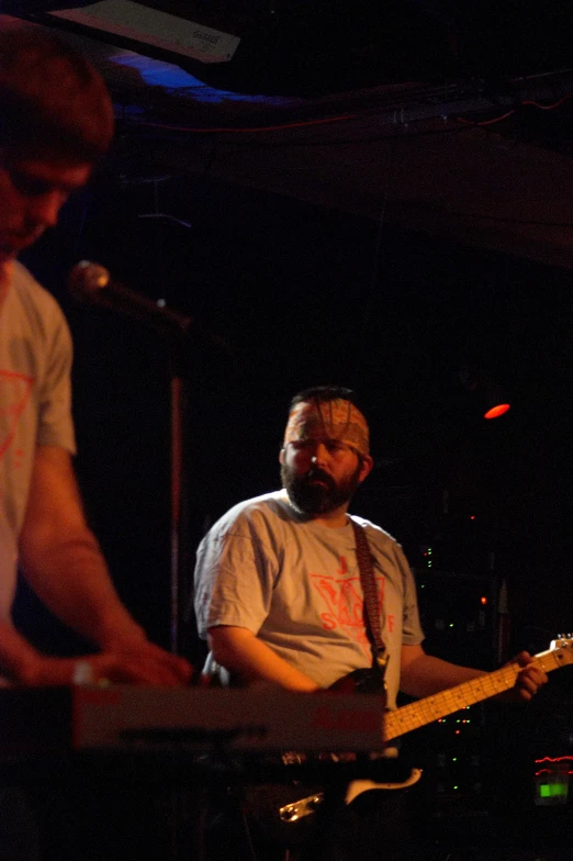 man in white shirt playing with another musician