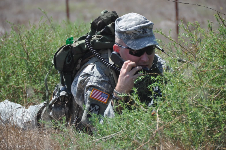 a soldier on a field talks on the phone