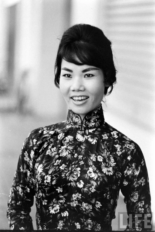 a woman wearing a top with a floral pattern and a black bun with an elaborate collar