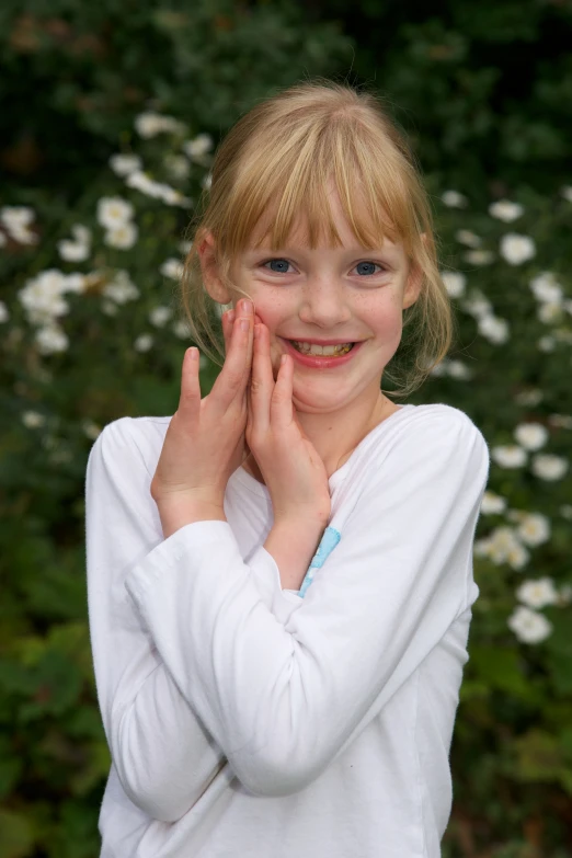 a little girl wearing a white shirt and smiling