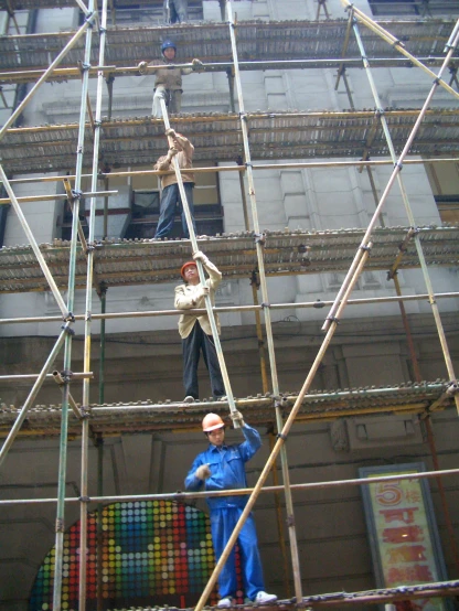 several workers in construction gear, standing on scaffolding