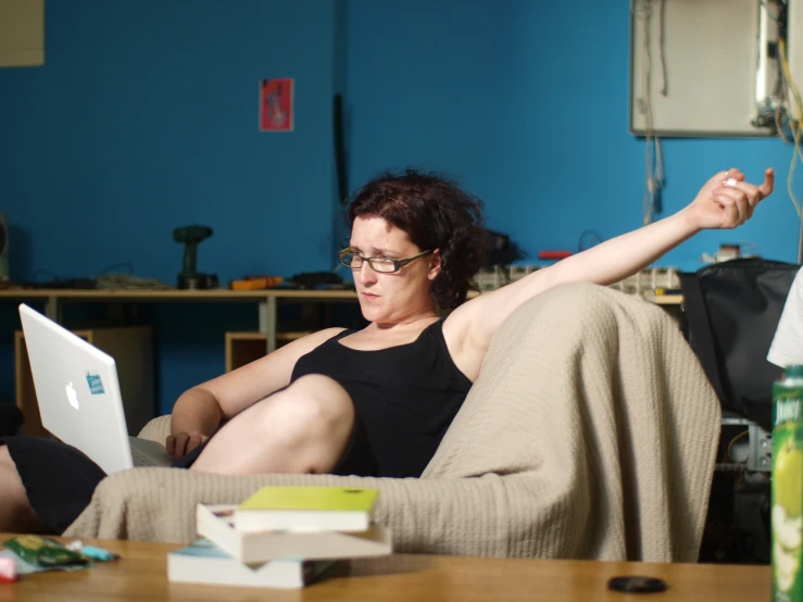 woman in glasses sitting on a couch using a laptop