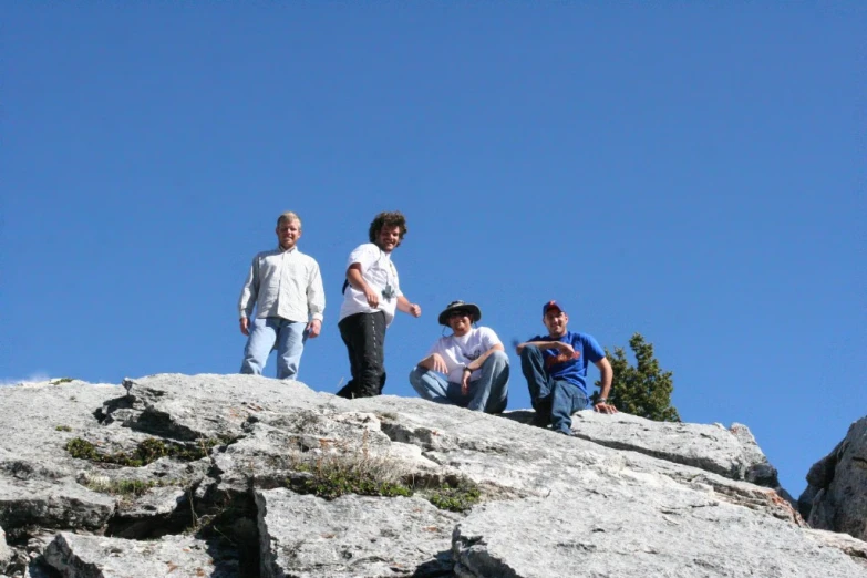 four people sitting on a rock in the sky