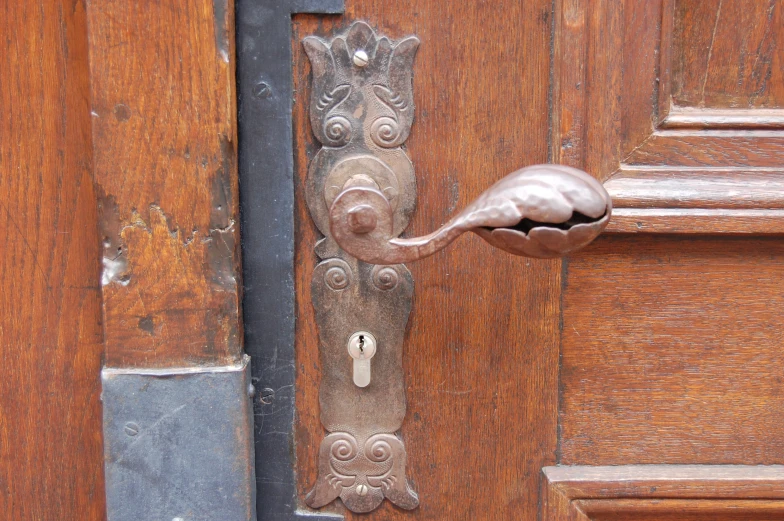 the front door has an ornate latch and is brown