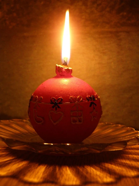 a close up of a lit candle on a plate