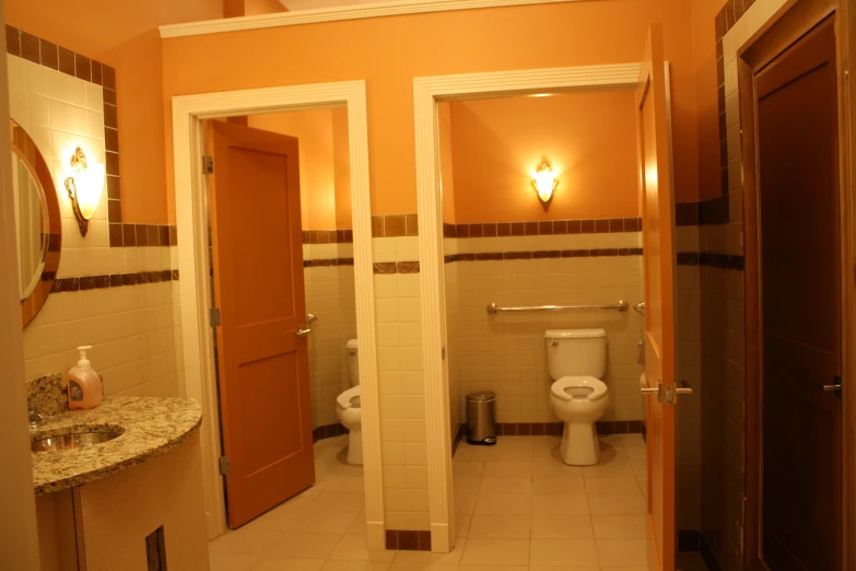 a small public bathroom with tiled floors and orange walls