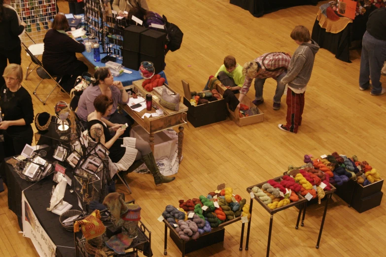 two people work at a table covered in yarn