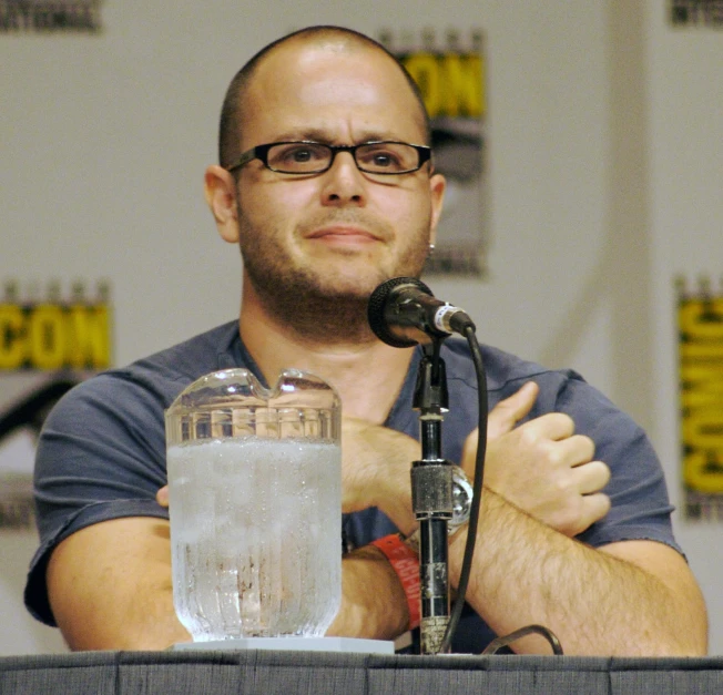 the man in glasses is sitting at a podium