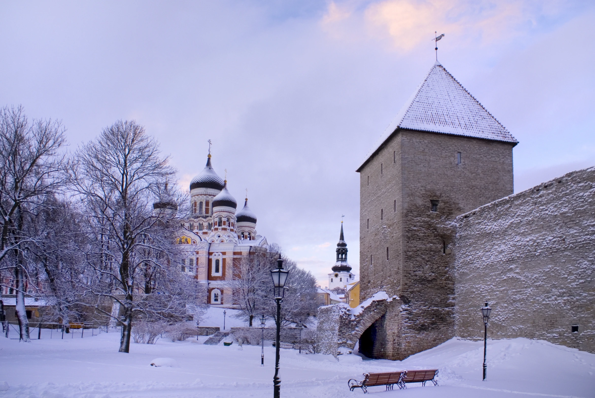 an old stone building with a tower next to a snowy park