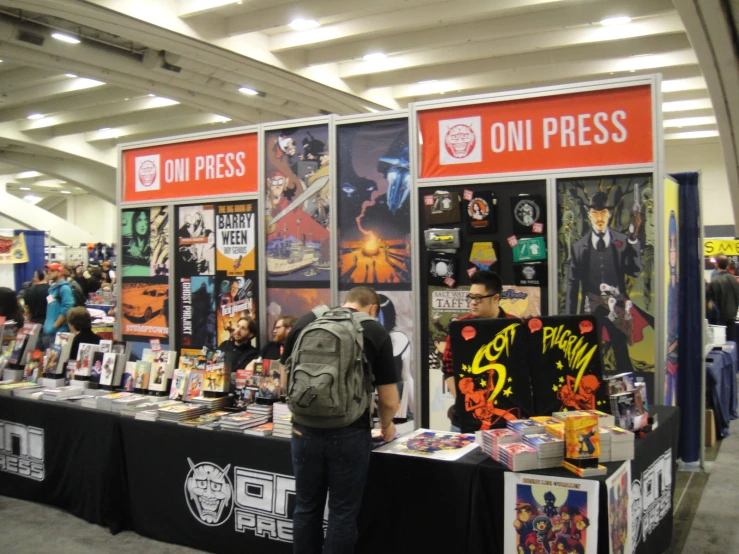 a man stands between two trade booths displaying comic books