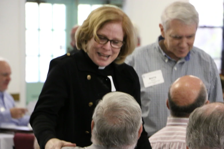 a nun is laughing as she holds out her hands to some other people