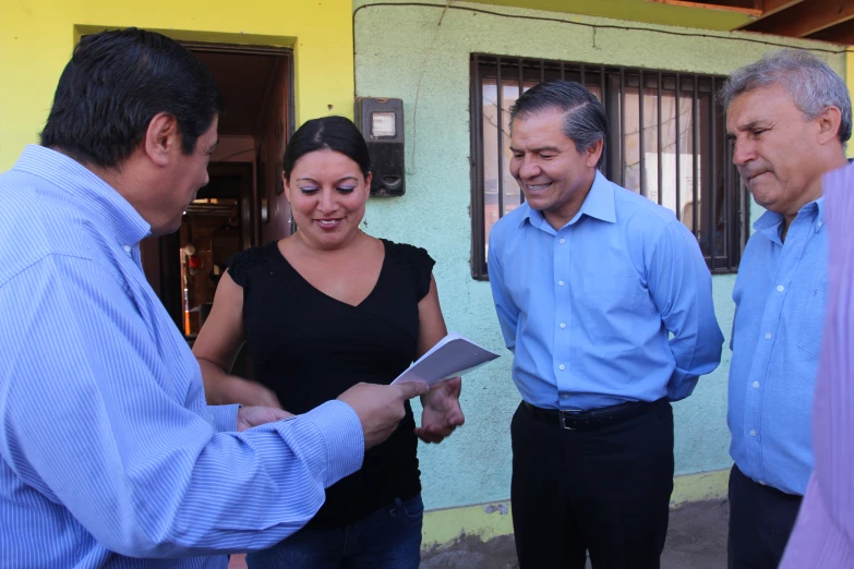 two adults are exchanging papers to another family outside