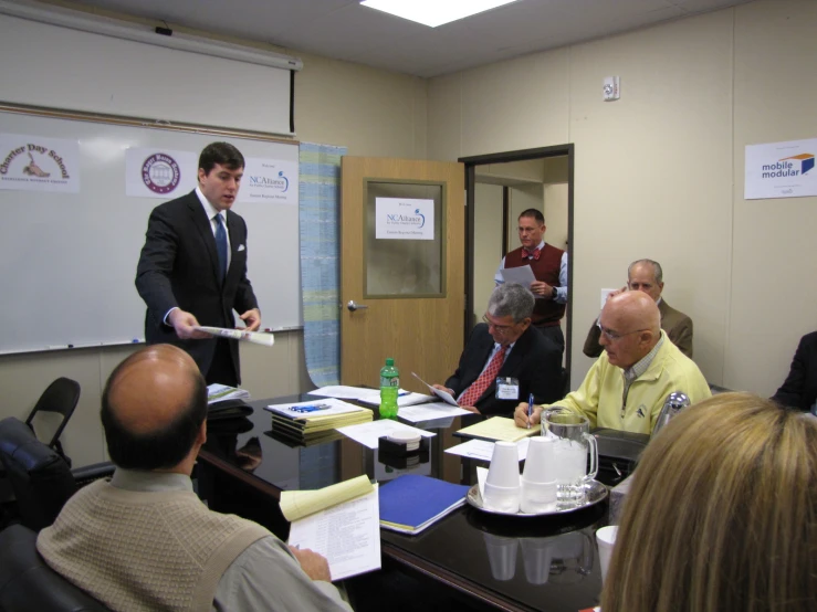 some people are gathered around a boardroom having meeting