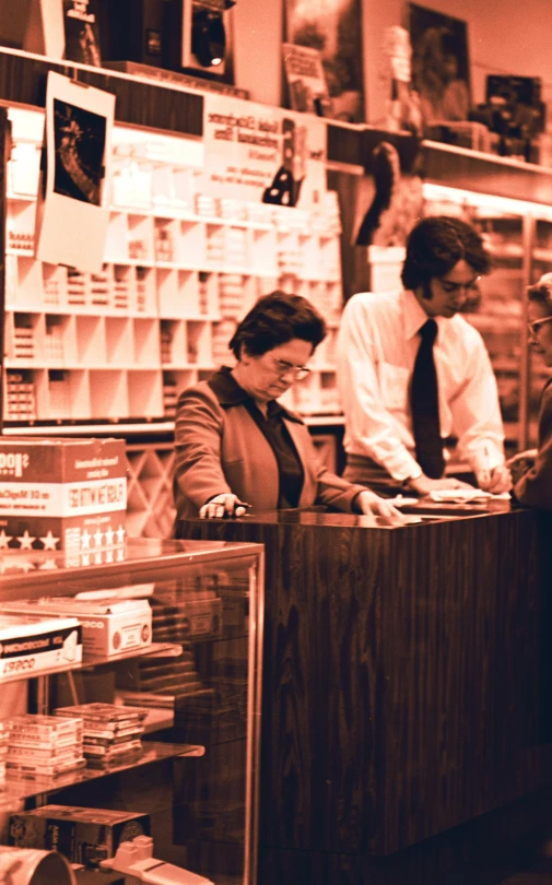 woman at the cash register with two men looking on