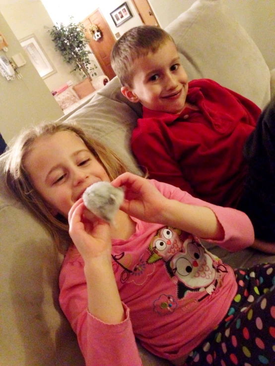 two children are playing video games on the couch