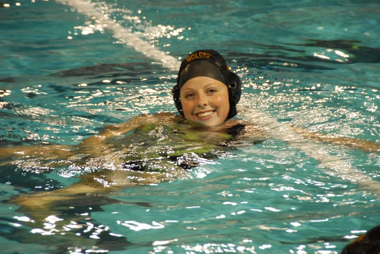 the girl is swimming on her knees and her smile is glowing