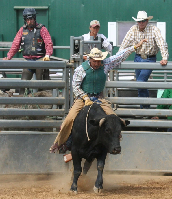 man is falling off his bull while another man watches