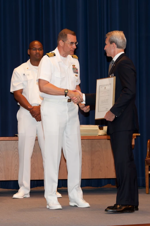 there is a man holding an award standing next to other men