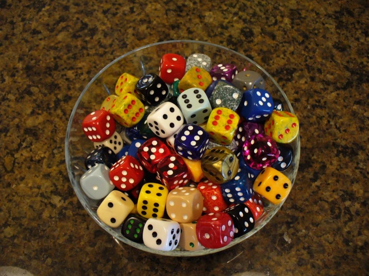 a bowl of plastic dice sitting on top of a table