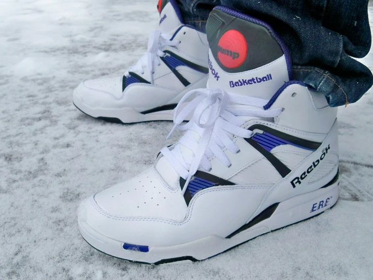 a pair of white and blue tennis shoes on a snow - covered ground