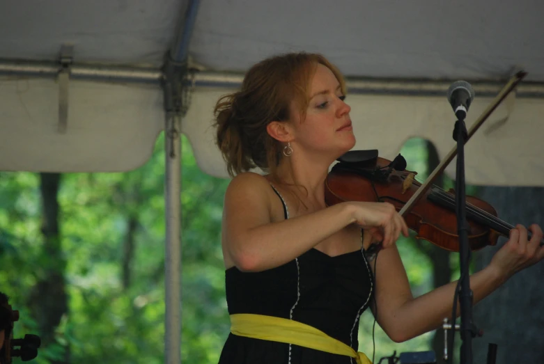 a beautiful woman playing the violin under a tent