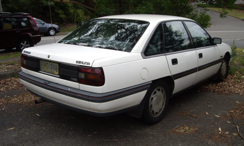 the back end of a white car parked on the side of the road