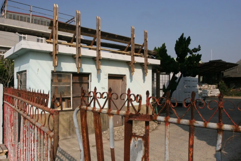 a house with metal fence posts and rusted gate