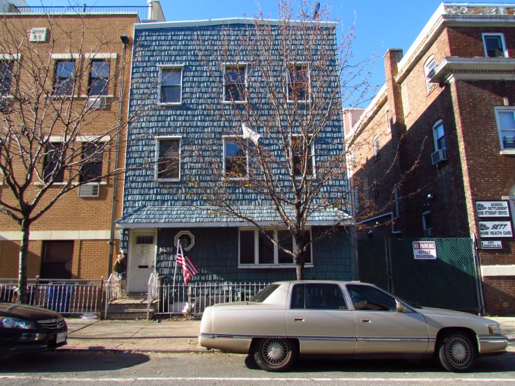 a car parked on a city street in front of a row of multi - family houses