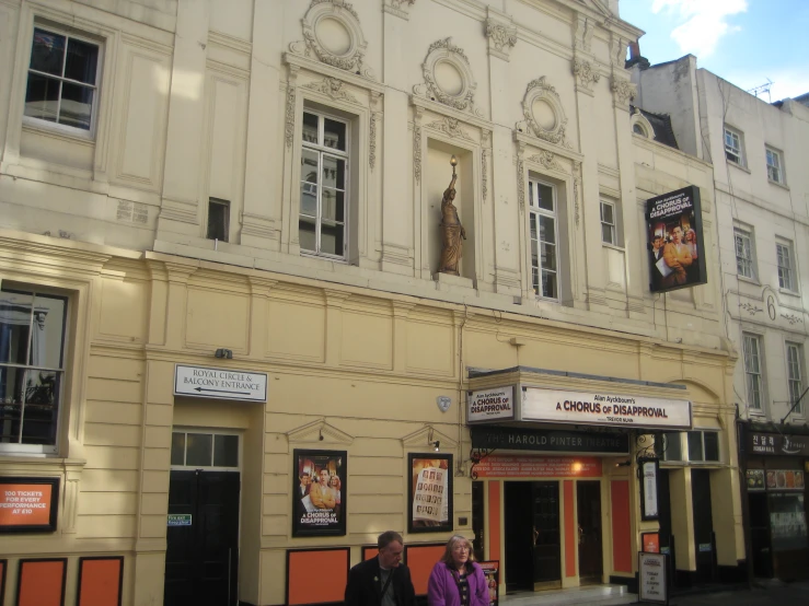 two people walking past the front entrance of a theatre