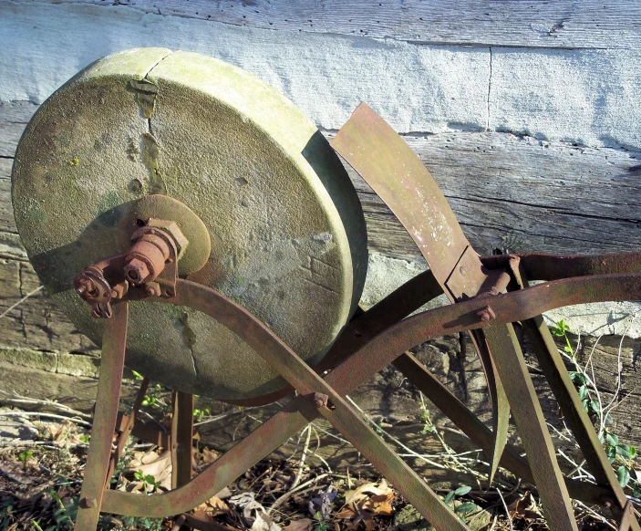 an old wheel that is leaning up against the wall