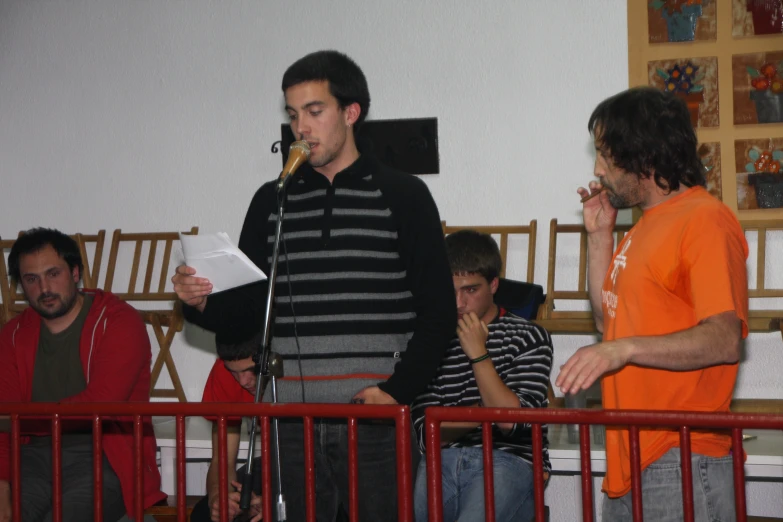 man speaking into microphone in front of other people