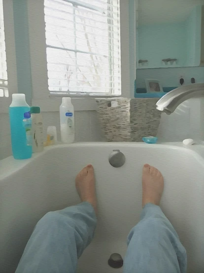 someones feet in the tub with a lot of soap and other containers