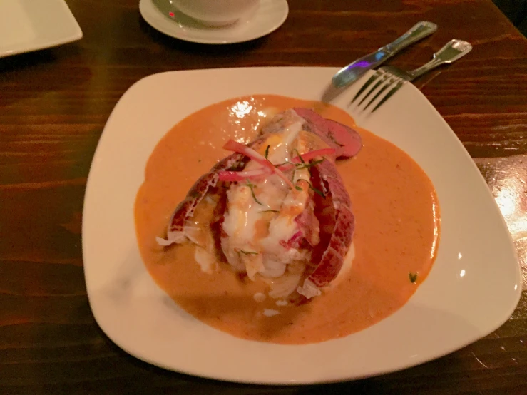 a plate on a wooden table with a lobster dish