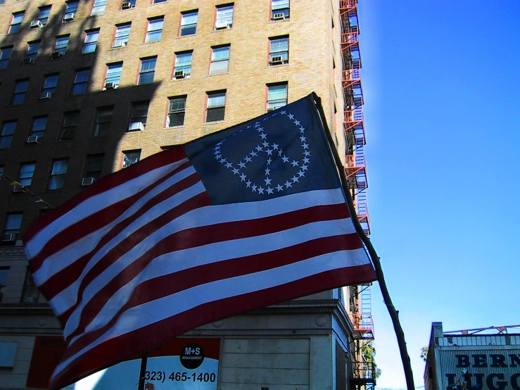 an american flag flying next to a tall building