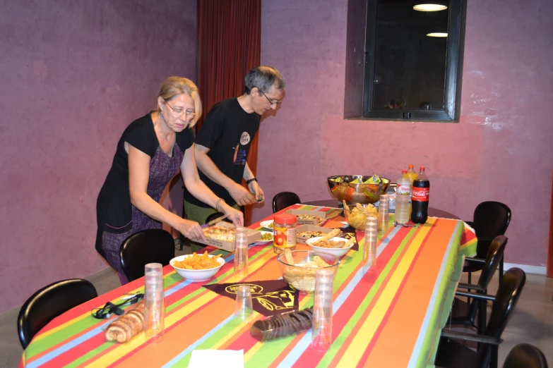 a man and woman are standing around a table in front of a cake