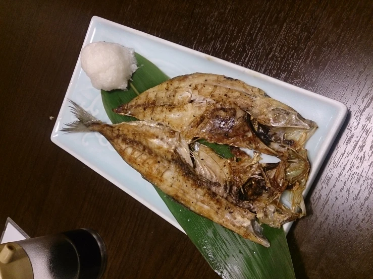 the cooked fish is on the plate next to a beer