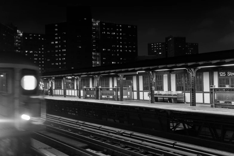 a train traveling past tall buildings at night