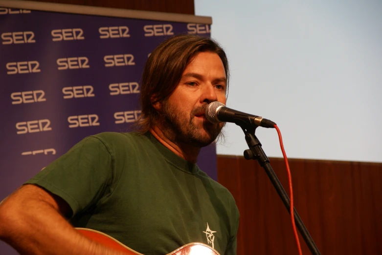 a man playing an acoustic guitar in front of a microphone