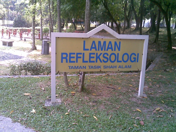 a yellow and blue sign sitting in front of a park