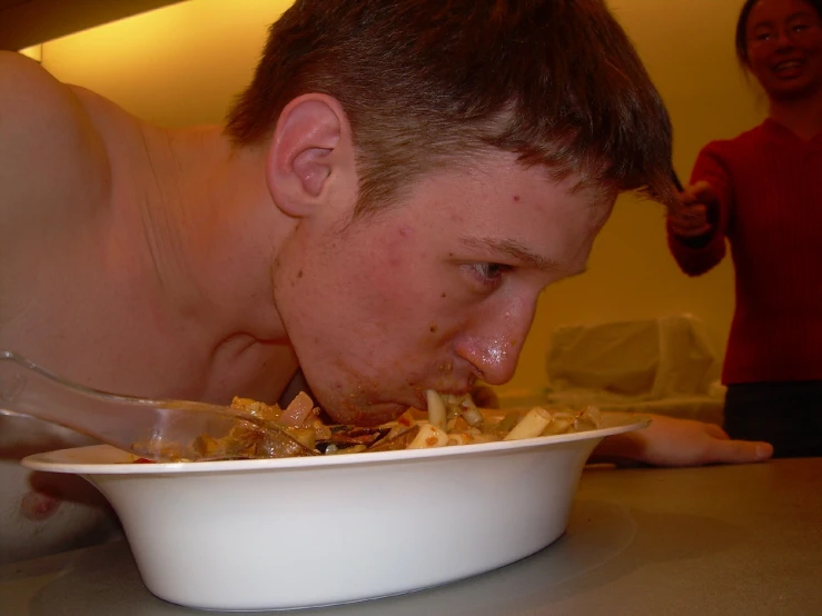 a man eats a plate of food while another man watches