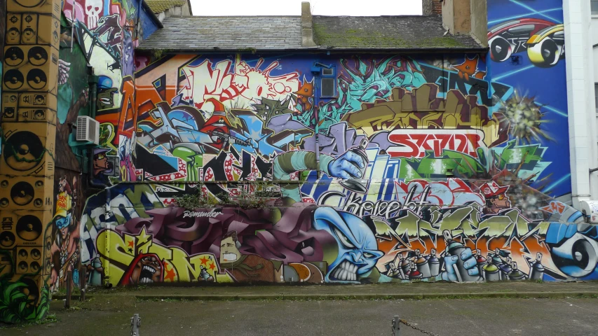 a wall full of graffiti on the side of the road