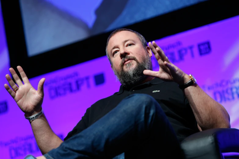 a bearded man is sitting down and talking