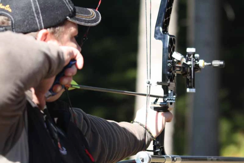 an older man is aiming a bow in the woods