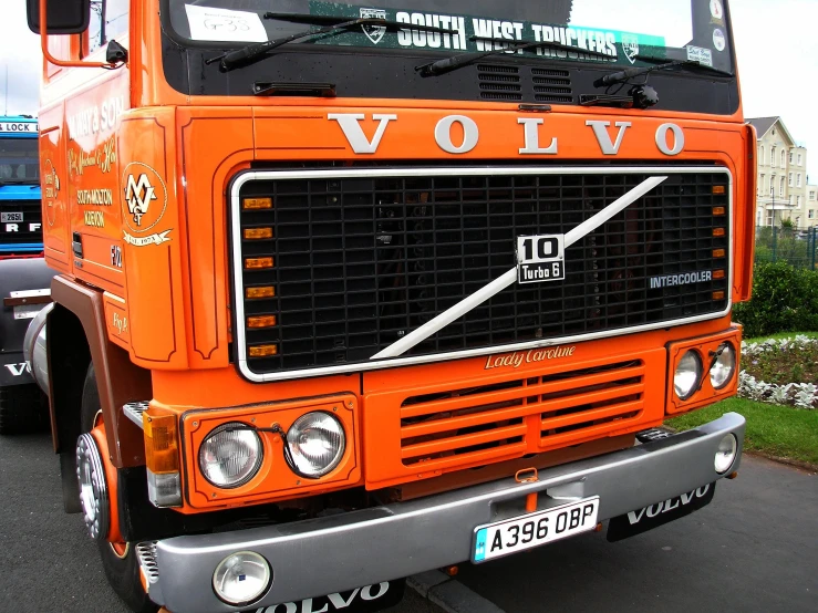 the front of an orange volvo truck parked in a parking lot