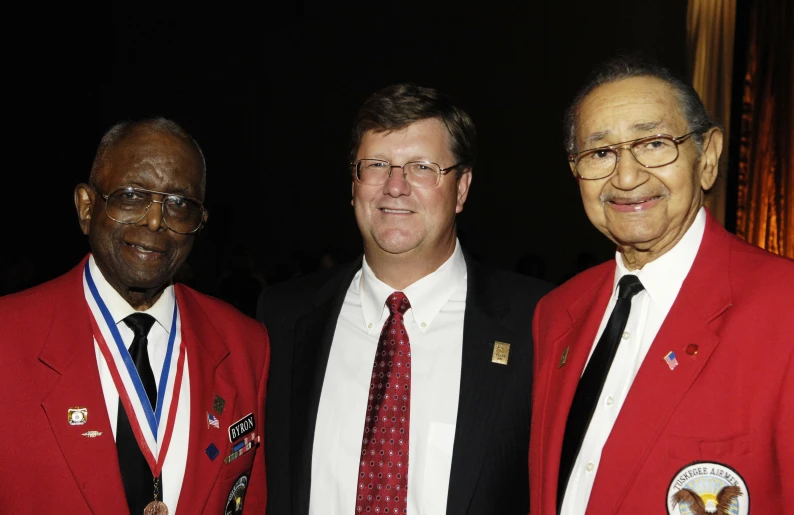 three men wearing suits posing for the camera