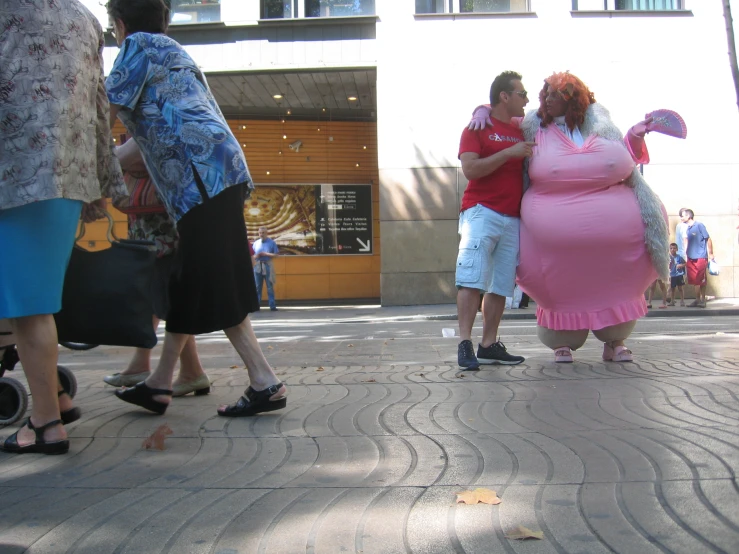 two pregnant women kissing on the sidewalk near a city street