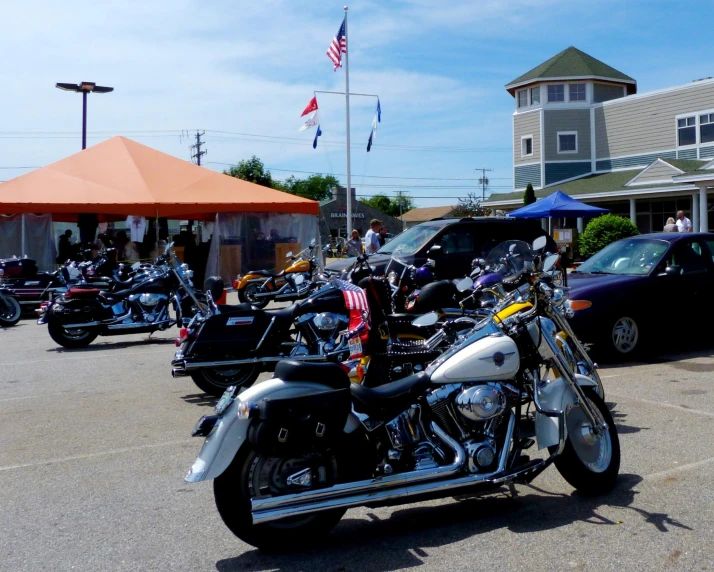 motorcycles are parked in the parking lot with several flags and some cars