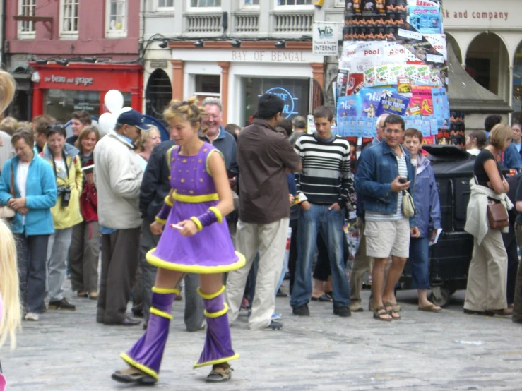 a girl dressed in a purple outfit walking across the street