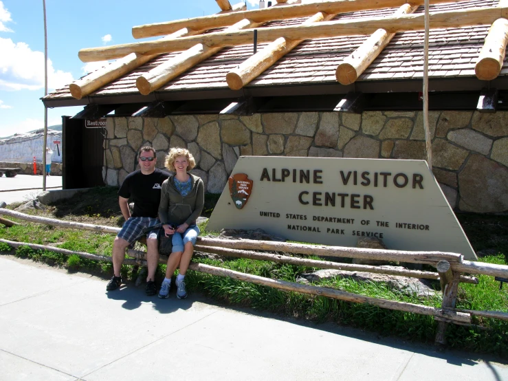 three people are posing for a po in front of alpine visitor center